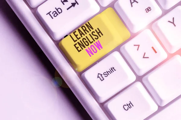 Writing note showing Learn English Now. Business photo showcasing gain or acquire knowledge and skill of english language White pc keyboard with note paper above the white background.