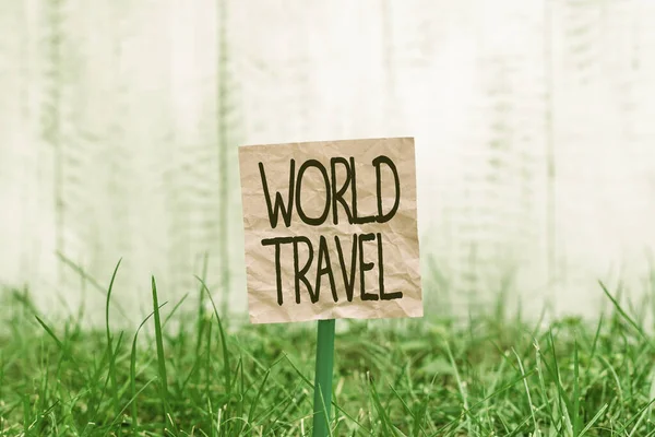 Conceptual hand writing showing World Travel. Business photo text the movement of showing between distant geographical locations Plain paper attached to stick and placed in the grassy land. — Stock Photo, Image