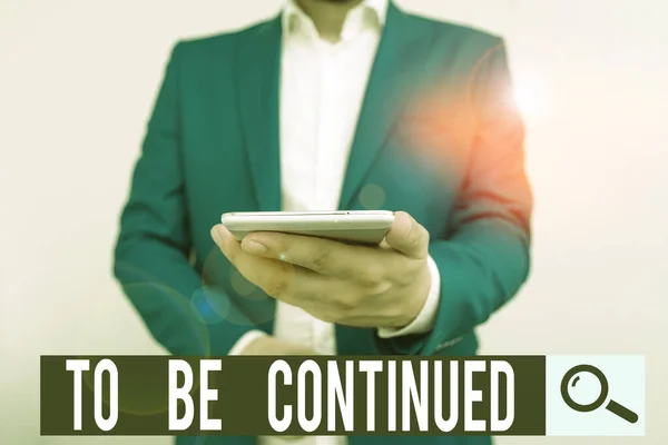 Writing note showing To Be Continued. Business photo showcasing indicate that the story continues in the next episode Business concept with man holding mobile phone with touch screen.