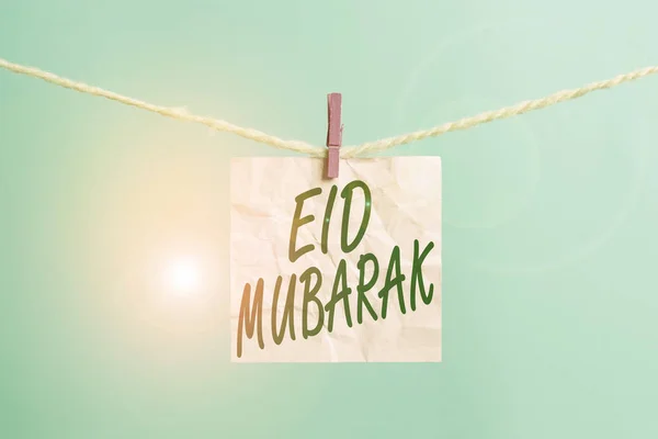 Signo de texto que muestra Eid Mubarak. Foto conceptual tradicional saludo musulmán reservado para los festivales sagrados tendedero pinza de ropa rectángulo en forma de papel recordatorio escritorio de madera blanca . — Foto de Stock