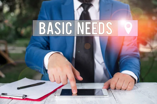 Writing note showing Basic Needs. Business photo showcasing something that you must have in order to sustain or live life Businessman with pointing finger in front of him.