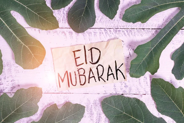 Conceptueel handschrift met Eid Mubarak erop. Zakelijke foto tekst traditionele islamitische begroeting gereserveerd voor de heilige festivals bladeren rond briefpapier boven een klassieke houten tafel. — Stockfoto