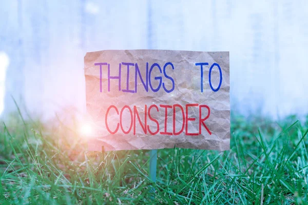 Word writing text Things To Consider. Business concept for think about carefully especially in making decisions Crumpled paper attached to a stick and placed in the green grassy land. — Stock Photo, Image