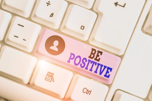 Conceptual hand writing showing Be Positive. Business photo text giving cause for hope and confidence Without any doubt White pc keyboard with note paper above the white background.