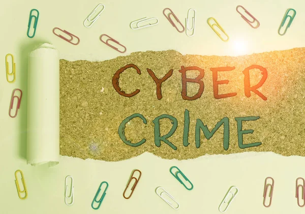 Handwriting text Cyber Crime. Concept meaning kind of criminal activities carried out by means of Internet Paper clip and torn cardboard placed above a wooden classic table backdrop.