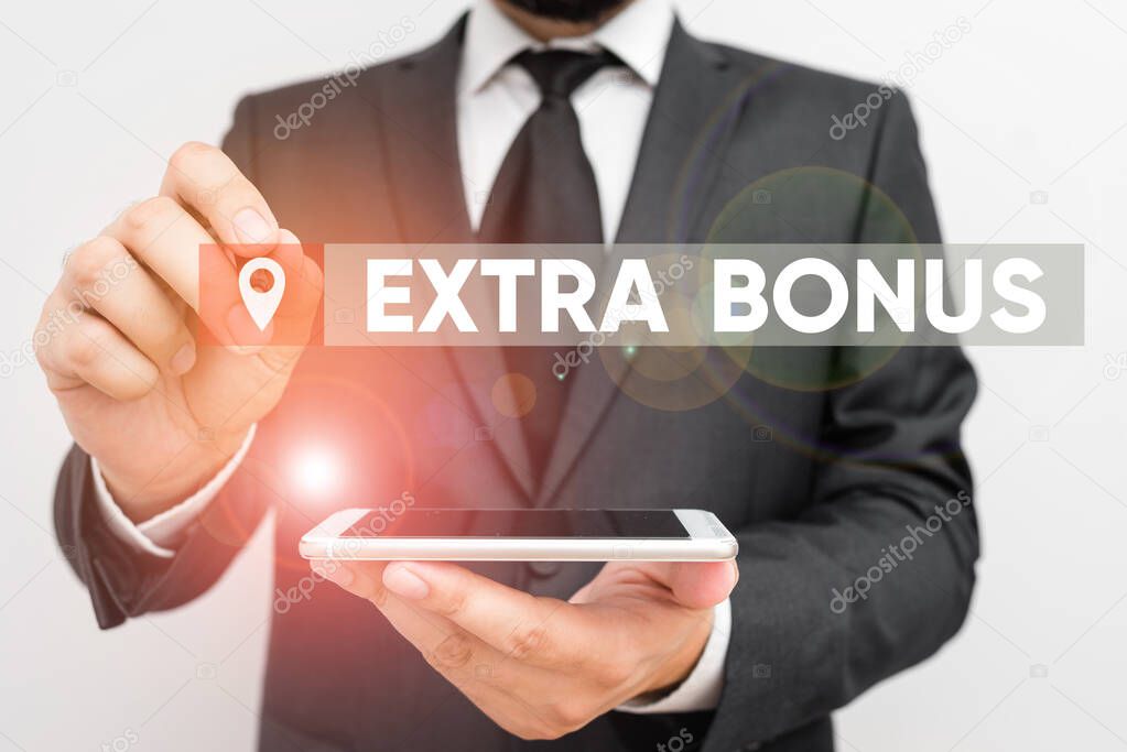 Conceptual hand writing showing Extra Bonus. Business photo text an extra amount of money that is added to someone s is pay Male human wear formal work suit hold smartphone using hand.