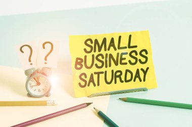 Cumartesi Küçük İşletme 'yi gösteren bir yazı. Kavramsal fotoğraf Amerikan alışveriş tatili Cumartesi Mini boyunda bir çalar saat Pastel arka planda sabit duruyor..