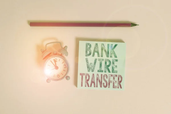Word writing text Bank Wire Transfer. Business concept for Electronic transfer of money through bank to bank Metal vintage alarm clock wakeup blank notepad marker colored background. — Stockfoto