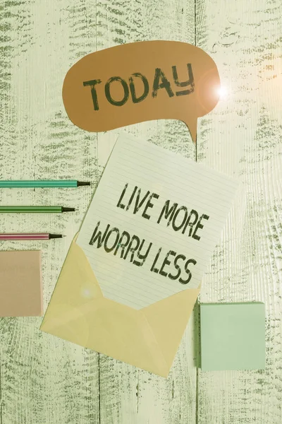 Writing note showing Live More Worry Less. Business photo showcasing Have a good attitude motivation be careless enjoy life Envelop speech bubble paper sheet ballpoints notepads wooden background. — Stock Photo, Image