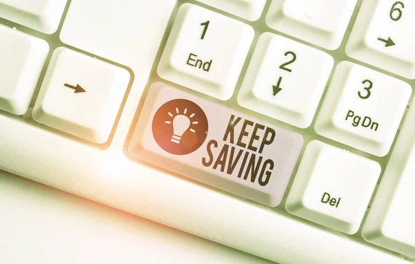 Writing note showing Keep Saving. Business photo showcasing keeping money in an account in a bank or financial organization White pc keyboard with note paper above the white background.