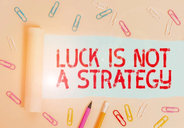 Writing note showing Luck Is Not A Strategy. Business photo showcasing it is not being Lucky when planned intentionally Stationary and torn cardboard placed above plain pastel table backdrop.