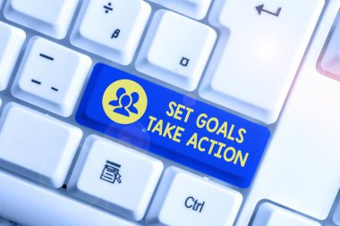 El yazısı: Set Goals Take Action. Beyaz arkaplan anahtar boşluğunun üzerinde boş not kağıdı bulunan ve açıkça belirtilmiş beyaz pc klavye planları için kavram anlamı.