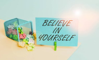 Kendine İnan 'ı gösteren bir not yazıyorum. İş fotoğraflarında özgüven teşviki çöp tenekesinden alıntılanan özgüven motivasyonu buruşuk kağıt çamaşır mandalı ofis malzemeleri.