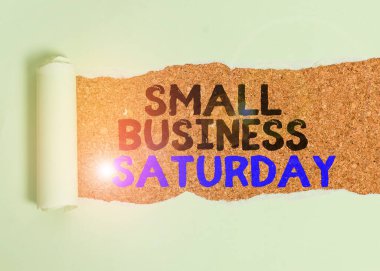 Cumartesi günü Small Business 'ı gösteren bir not yazıyorum. İş fotoğraflarında Amerikan alışveriş tatili gösteriliyor. Klasik ahşap bir masanın üzerine yerleştirilen cumartesi kartonunda..