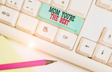 Anneme en iyisi olduğunu gösteren bir mesaj. Annen için kavramsal fotoğraf değerlendirmesi beyaz arkaplan anahtar boşluğunun üzerinde boş not kağıdıyla beyaz pc klavyesine iltifat etmeyi sever..