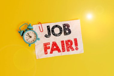 Text sign showing Job Fair. Conceptual photo event where employers offer information about their companies Metal alarm clock clip blank crushed note sheet colored background.