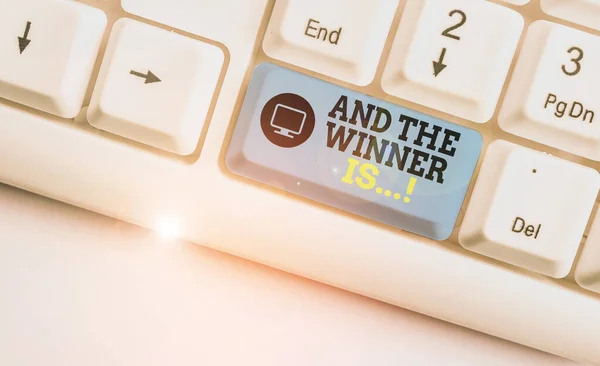 Handwriting text writing And The Winner Is. Concept meaning announcing who got first place at competition or exam White pc keyboard with empty note paper above white background key copy space. — Stock Photo, Image