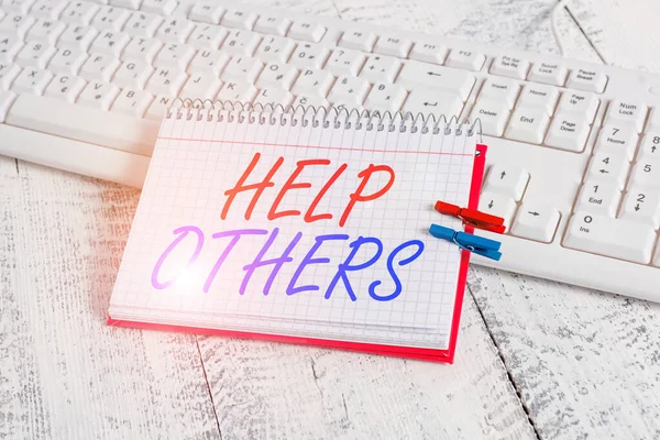 Handwriting text writing Help Others. Concept meaning the action of helping someone to do something or assistance notebook paper reminder clothespin pinned sheet white keyboard light wooden.