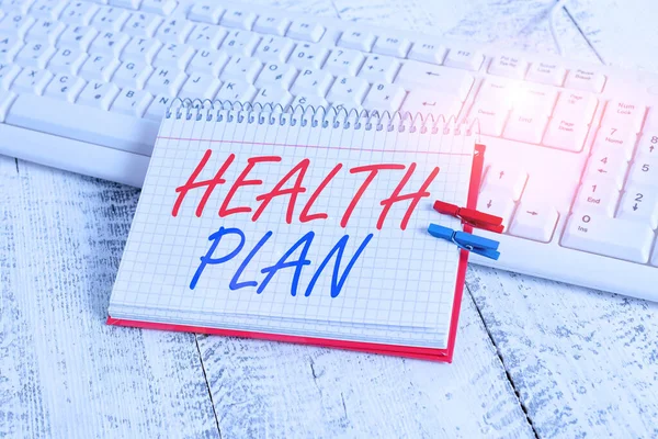 Handwriting text writing Health Plan. Concept meaning entity that provides coverage of designated health services notebook paper reminder clothespin pinned sheet white keyboard light wooden. — Stock Photo, Image