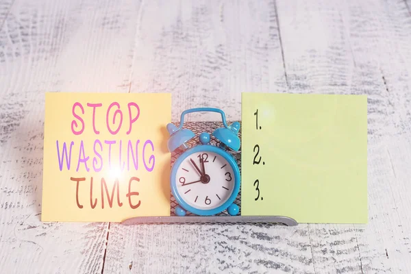 Writing note showing Stop Wasting Time. Business photo showcasing Organizing Management Schedule lets do it Start Now Mini blue alarm clock standing above buffer wire between two paper. — Stok fotoğraf