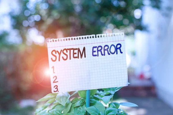 Text sign showing System Error. Conceptual photo instruction that is not recognized by an operating system Plain empty paper attached to a stick and placed in the green leafy plants.