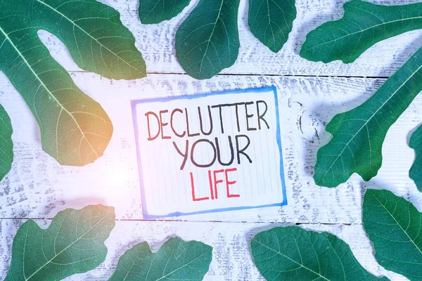 Handwriting text Declutter Your Life. Concept meaning To eliminate extraneous things or information in life Leaves surrounding notepaper above a classic wooden table as the background. — Stock Photo, Image