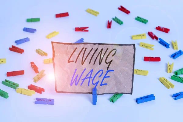 Handwriting text writing Living Wage. Concept meaning wage that is high enough to maintain a normal standard of living Colored clothespin papers empty reminder white floor background office.
