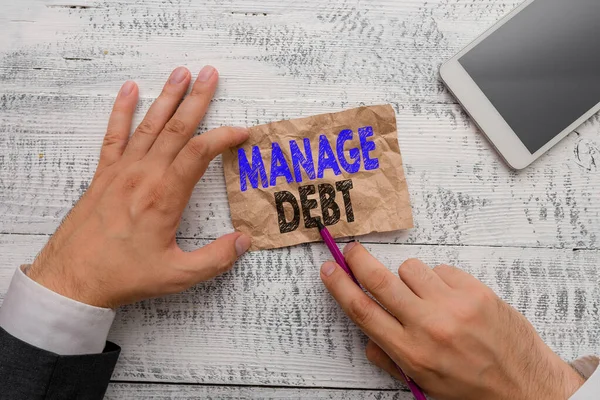 Conceptual hand writing showing Manage Debt. Business photo showcasing unofficial agreement with unsecured creditors for repayment Hand hold note paper near writing equipment and smartphone.