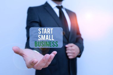 El yazısı metni Küçük İş Başlat. Bu da demek oluyor ki, girişimci olmak isteyen bir Yeni Girişim Sanayicisi sakallı bir erkek işçi kıyafeti giyip bir elini havaya kaldırıyor..