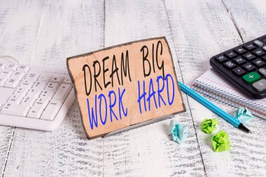 Dream Big Work Hard 'ı gösteren bir not yazıyorum. İş fotoğrafı gösterimi Kendine inan ve hayalleri ve hedefleri takip et. Bilgisayar klavyesi ve kağıtları arasında tel üzerine not al..