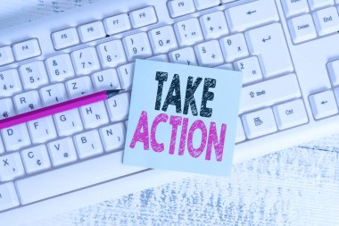 Take Action 'ı gösteren bir not yazıyorum. Klavye ofisi, dikdörtgen şekilli kağıt hatırlatıcı ahşap malzemelerini belirli bir sonuç elde etmek için bir şeyler yapmak için iş fotoğrafı sergiliyor..