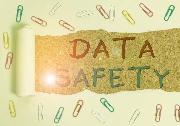 Handwriting text Data Safety. Concept meaning concerns protecting data against loss by ensuring safe storage Paper clip and torn cardboard placed above a wooden classic table backdrop.