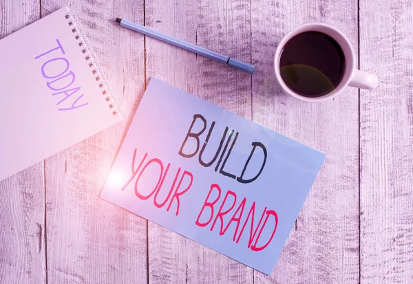 자신의 브랜드를 만드는 것을 보여 주는 글쓰기. 광고 캠페인을 사용하여 브랜드의 공정성을 강화하는 비즈니스 사진, 나무 탁자 위에 있는 검은 커피 컵 옆에 멈춰 있는 광고. — 스톡 사진