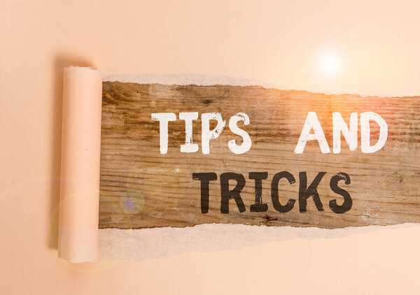 Handwriting text Tips And Tricks. Concept meaning piece of inside facts specially in betting or investing Cardboard which is torn in the middle placed above a wooden classic table.