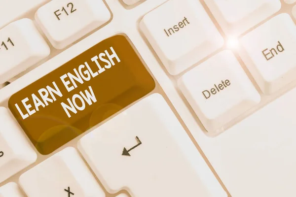 Escribir nota mostrando Aprender inglés ahora. Foto de negocios mostrando ganancia o adquirir conocimientos y habilidades de idioma Inglés Teclado blanco PC con papel de nota sobre el fondo blanco . —  Fotos de Stock