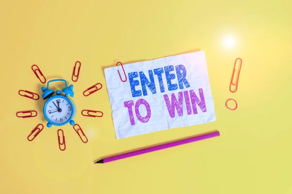 Handwriting text Enter To Win. Concept meaning exchanging something value for prize or chance of winning Metal alarm clock clips crushed sheet pencil rubber band colored background.