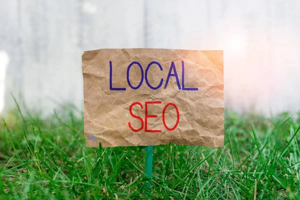 Word writing text Local Seo. Business concept for helps businesses promote products and services to local customers Crumpled paper attached to a stick and placed in the green grassy land. — Stock Photo, Image