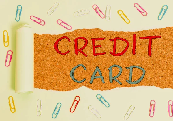 Handwriting text Credit Card. Concept meaning card that allows you to borrow money against a line of credit Paper clip and torn cardboard placed above a wooden classic table backdrop.