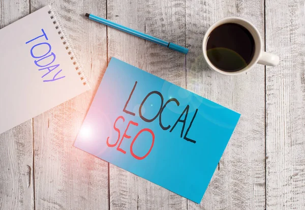 Writing note showing Local Seo. Business photo showcasing helps businesses promote products and services to local customers Stationary placed next to a cup of black coffee above the wooden table. — Stock Photo, Image