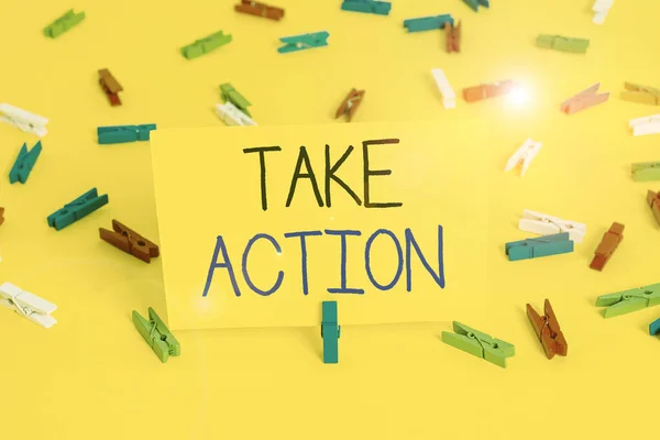 Text sign showing Take Action. Conceptual photo to do somethingoract in order to get a particular result Colored clothespin papers empty reminder yellow floor background office.