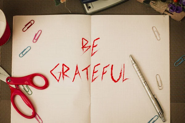 Text sign showing Be Grateful. Conceptual photo feeling or showing an appreciation for something received Scissors and writing equipments plus math book above textured backdrop. — ストック写真