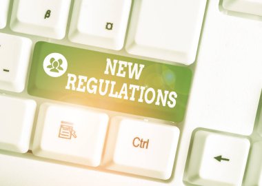 Handwriting text New Regulations Question. Concept meaning rules made government order control way something is done White pc keyboard with empty note paper above white background key copy space.