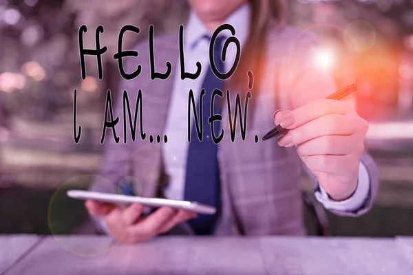 Writing note showing Hello I Am New. Business photo showcasing introducing oneself in a group as fresh worker or student Female business person sitting by table holding mobile phone. — Stock Photo, Image