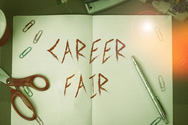 Text sign showing Career Fair. Conceptual photo an event at which job seekers can meet possible employers Scissors and writing equipments plus math book above textured backdrop.