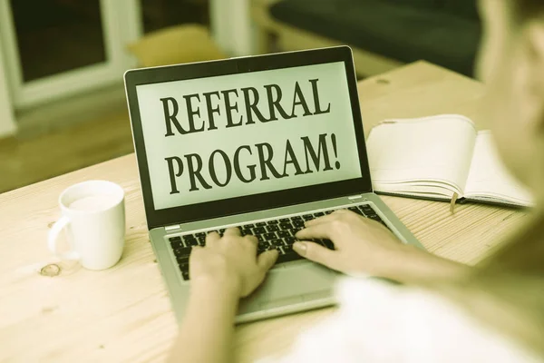 Word writing text Referral Program. Business concept for employees are rewarded for introducing suitable recruits woman laptop computer smartphone mug office supplies technological devices.