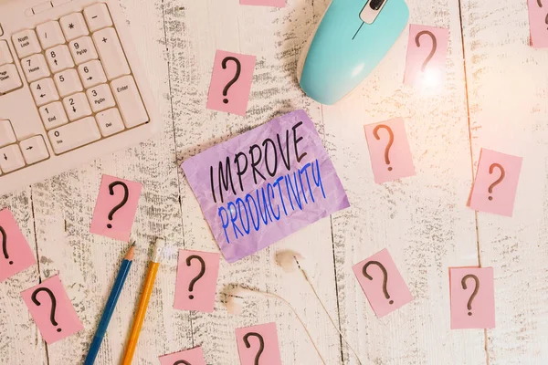 Writing note showing Improve Productivity. Business photo showcasing to increase the machine and process efficiency Writing tools and scribbled paper on top of the wooden table.