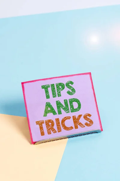 Word writing text Tips And Tricks. Business concept for helpful advices that makes certain action easier to do Paper placed tilted above buffer wire on soft pastel multi colours backdrop.