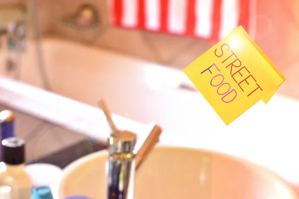 単語テキストストリートフードを書く。路上その他の公共の場で販売される調理食品の事業コンセプト洗面所ミラーに表記棒を与えるために使用する正方形の黄色のシートの一部. — ストック写真