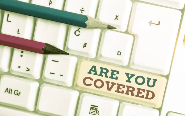 Writing note showing Are You Covered. Business photo showcasing Asking about how medications are covered by your plan White pc keyboard with note paper above the white background.