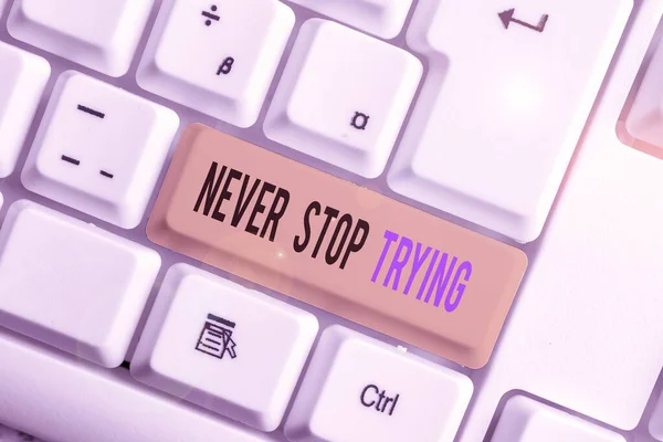 Text sign showing Never Stop Trying. Conceptual photo Do not give up Continue to Try Again Keep on Doing White pc keyboard with empty note paper above white background key copy space.